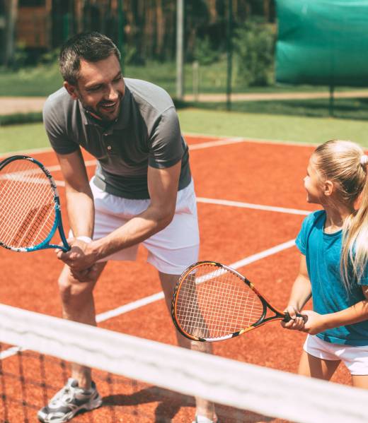 Practicing tennis. Cheerful father in sports clothing teaching h