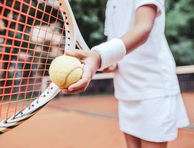 Sporty little girl preparing to serve tennis ball